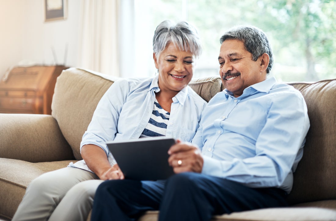 a man and a woman sitting on a couch using a laptop